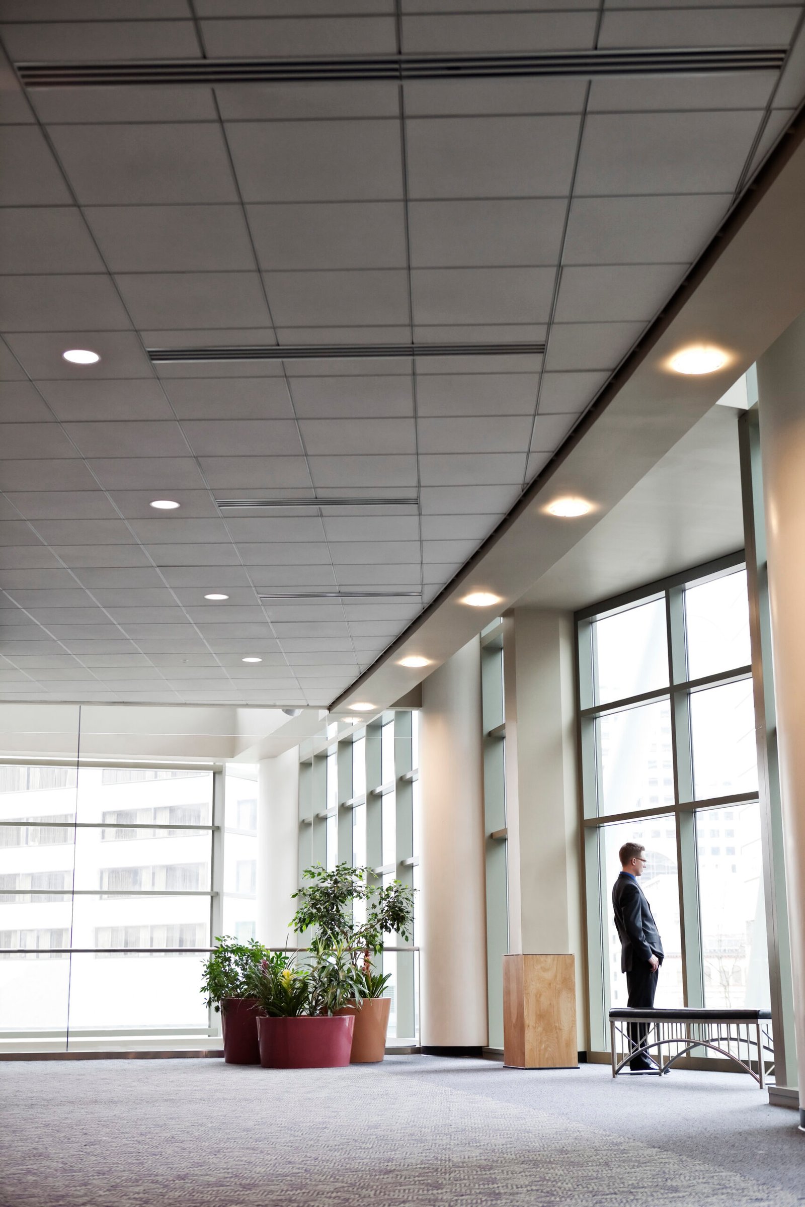 A businessman standing at a window in a large convention center lobby.