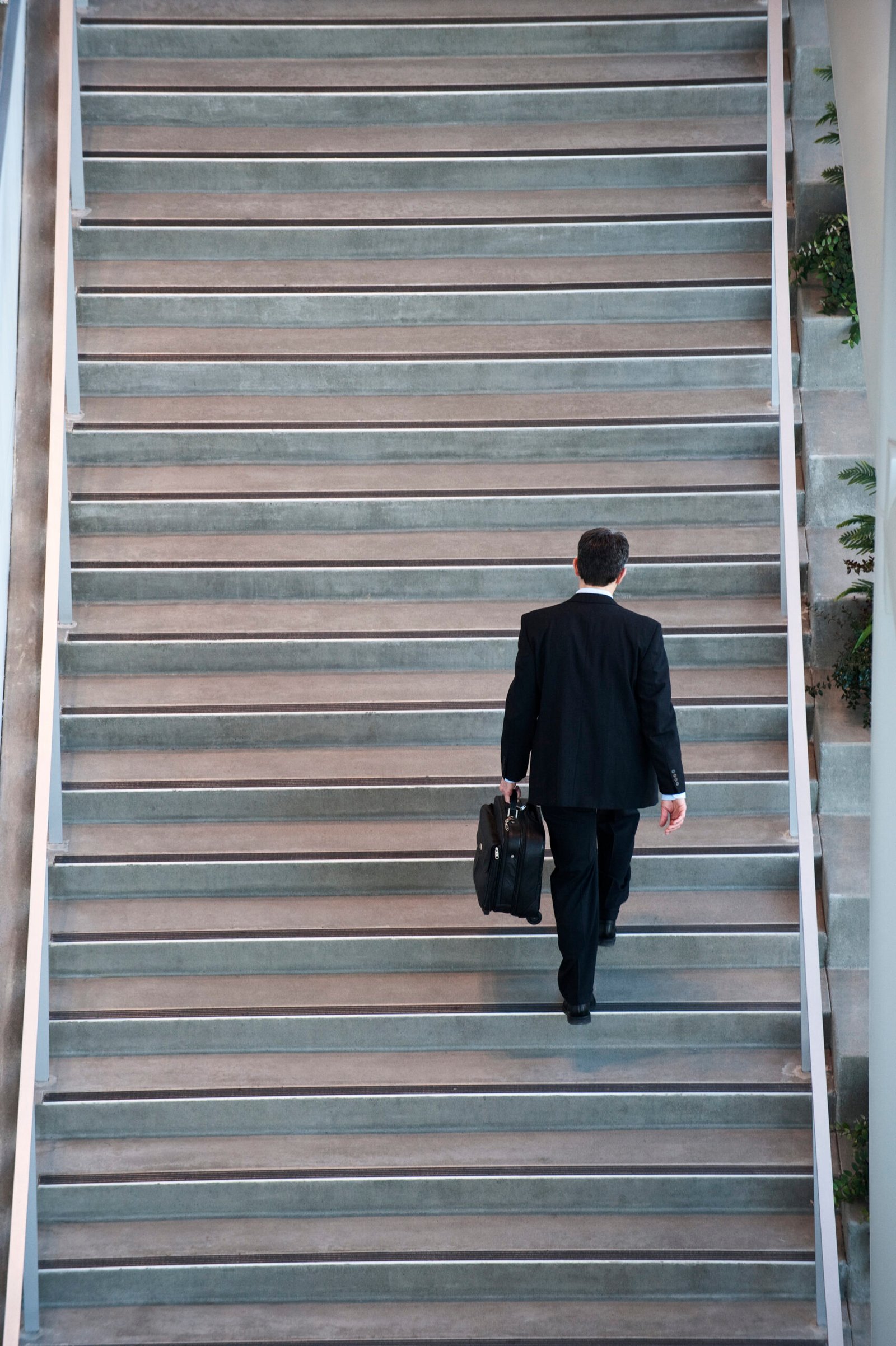 View from above looking down on a businessman walking up stairs in a conference centre lobby.